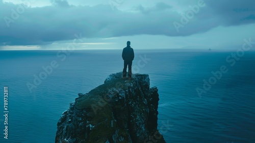 A pilot stands on the edge of a breathtaking cliff overlooking a vast expanse of ocean. The endless horizon behind him represents the boundless opportunities and challenges that come . photo