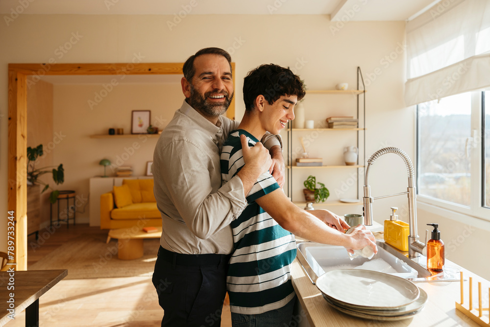 Father and son washing dishes at home Father and son washing dishes at home