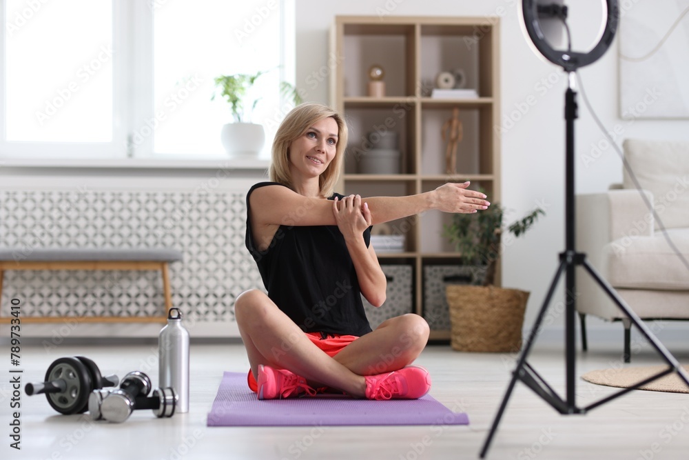 Smiling sports blogger streaming online fitness lesson with smartphone at home Smiling sports blogger streaming online fitness lesson with smartphone at home