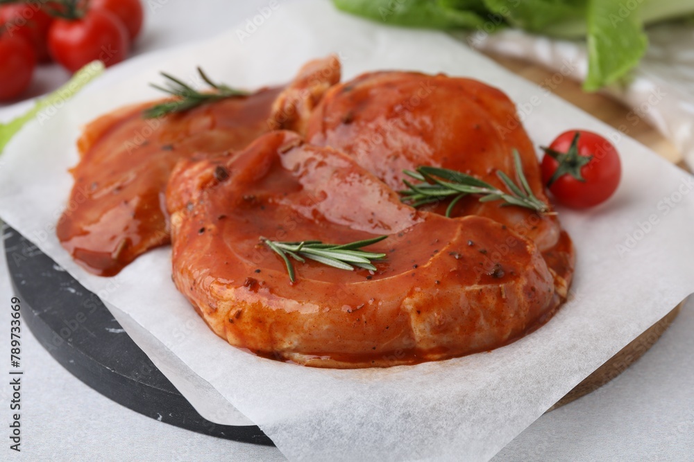 Board with raw marinated meat and rosemary on light table, closeup Board with raw marinated meat and rosemary on light table, closeup