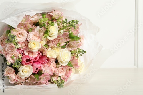 Beautiful bouquet of fresh flowers on wooden table near white wall, space for text © New Africa