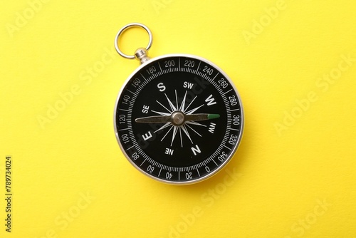 One compass on yellow background, top view. Tourist equipment