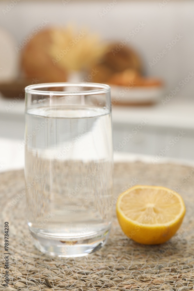 Glass with clear water and half of lemon on table in kitchen Glass with clear water and half of lemon on table in kitchen
