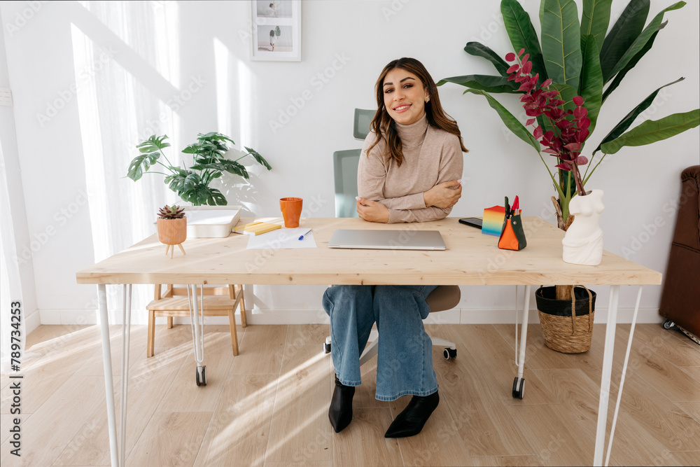 Smiling entrepreneur sitting with arms crossed in workplace Smiling entrepreneur sitting with arms crossed in workplace