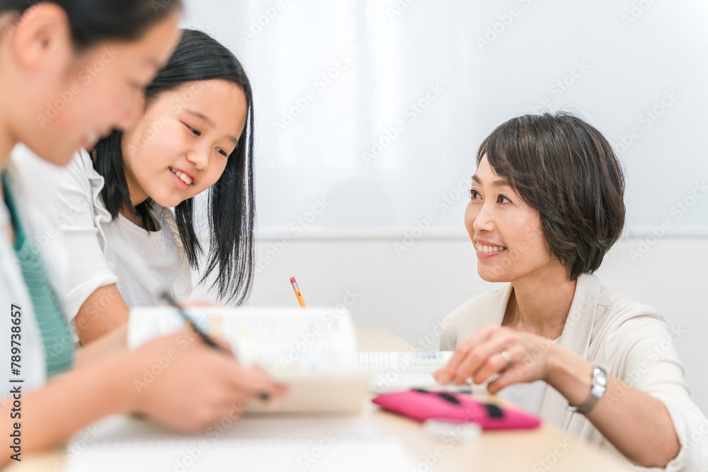 塾で先生に質問する小学生高学年のアジア人の女の子と女性講師
塾で先生に質問する小学生高学年のアジア人の女の子と女性講師