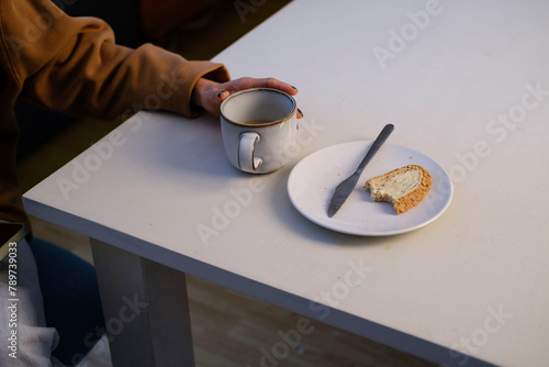 Crop of anonymous Woman's hand holding coffee cup and toast