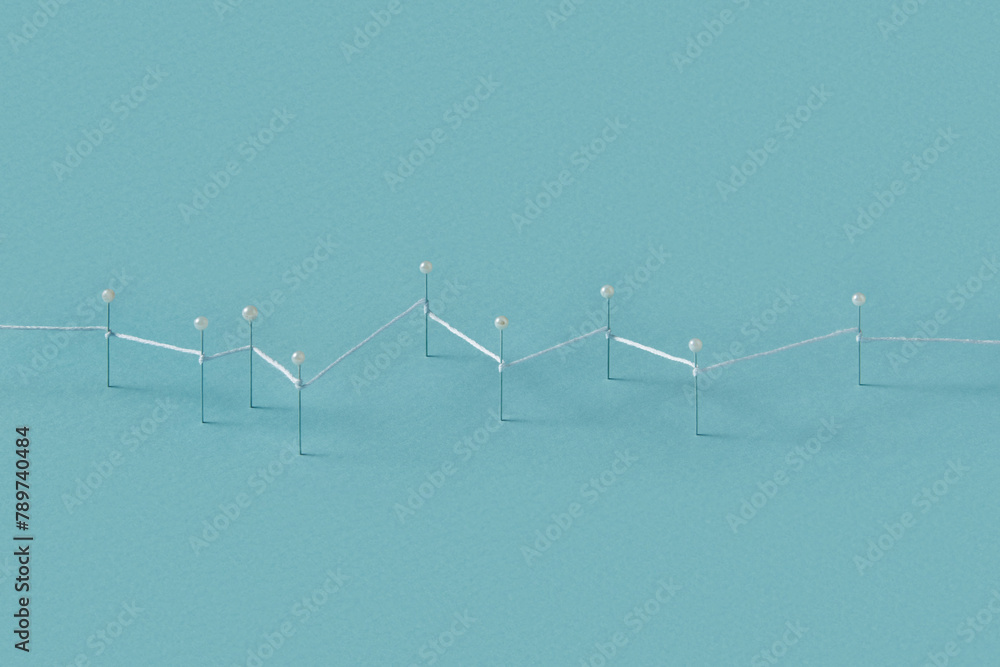 Stationery pins connected with thread and stuck in blue paper Stationery pins connected with thread and stuck in blue paper