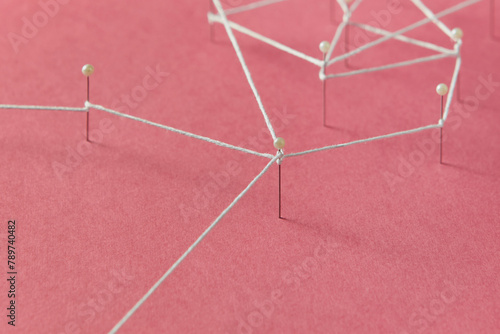 Stationery push pins connected with thread stuck on red paper photo