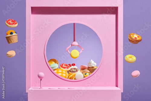 claw crane holders macaron with pastry in a gripper machine photo