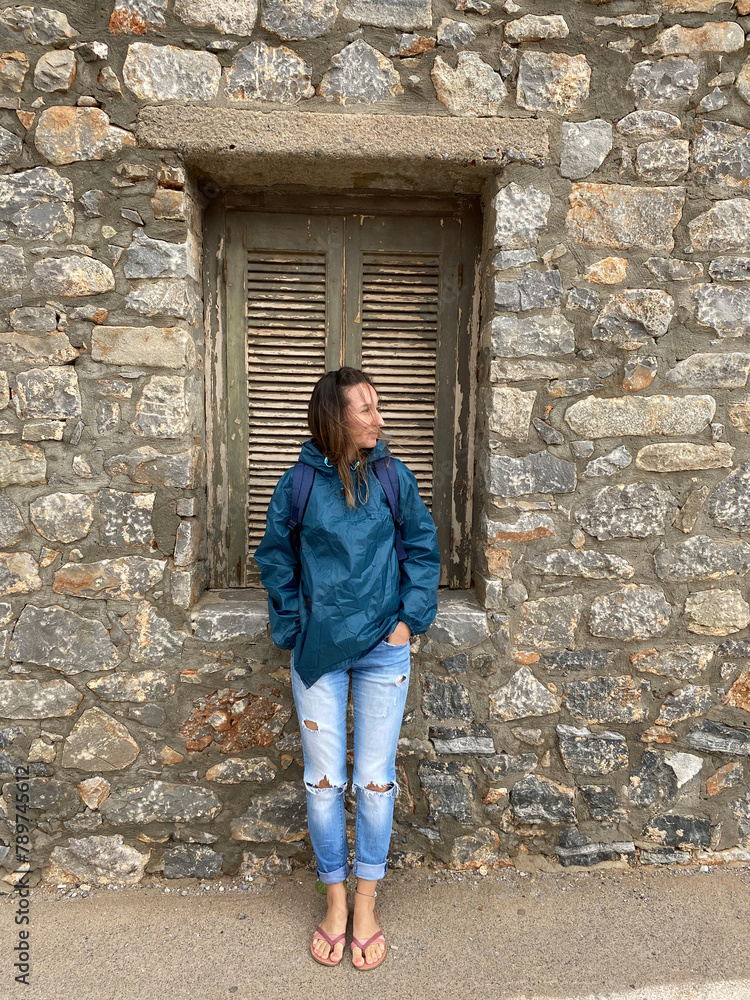 A young girl in torn jeans stands leaning against the wall. A young girl in torn jeans stands leaning against the wall.