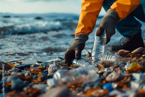 Person with rubber gloves cleans the plastic garbage waste on the beach shore of the ocean photo