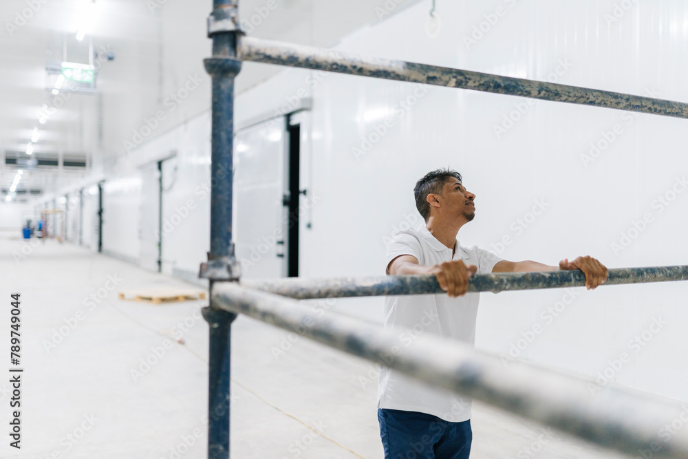 Man standing by steel scaffold while in hallway of modern building Man standing by steel scaffold while in hallway of modern building