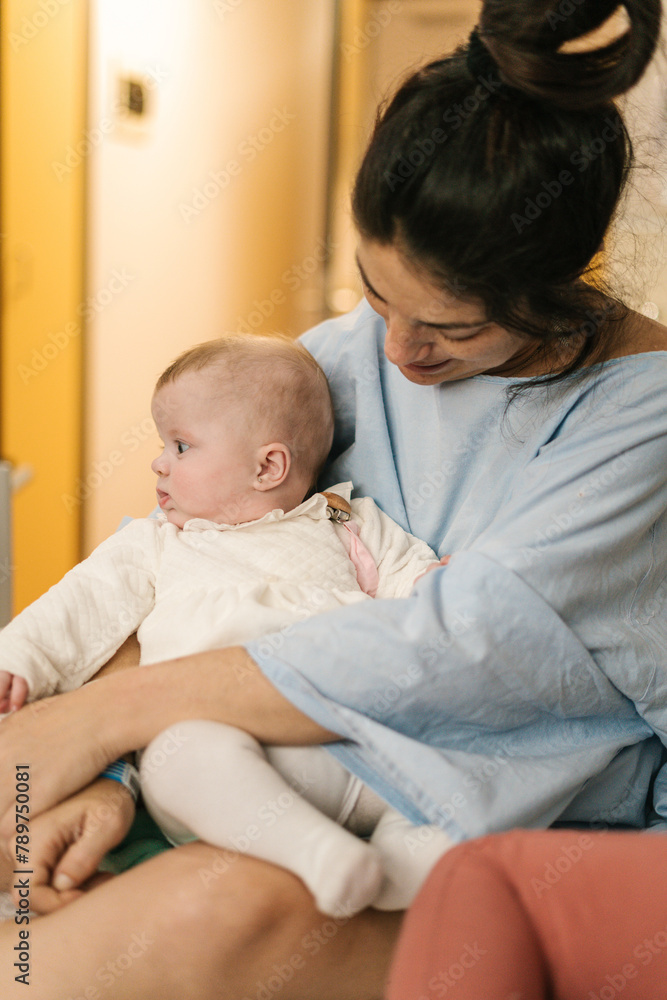 Woman sitting and carrying cute baby in hospital Woman sitting and carrying cute baby in hospital