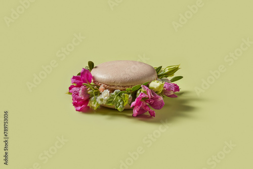 Delicious pink macaron decorated with fresh colorful flowers