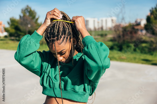Young black woman putting up her braided hair outdoors photo