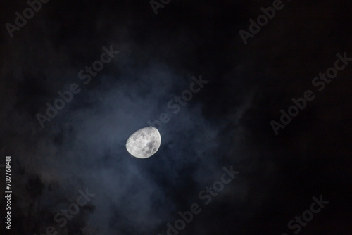 Full moon in the night sky with dark clouds, closeup of photo