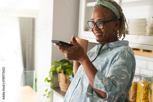 A senior African American woman is holding a smartphone at home, copy space photo