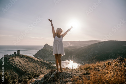 woman standing hill with her arms raised in the air, looking up at the sun. The scene is peaceful and serene, with the woman's expression conveying a sense of joy and happiness.