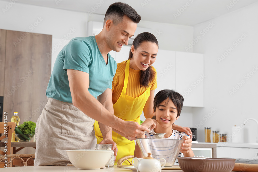 Happy parents with their little son preparing dough in kitchen Happy parents with their little son preparing dough in kitchen