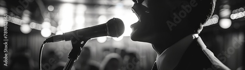 A black and white photo of a man singing into a microphone. photo