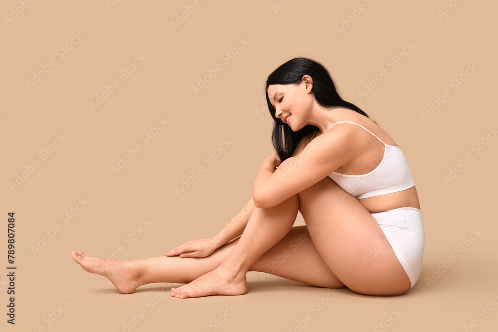 Fototapeta premium Body positive woman in underwear sitting on beige background
