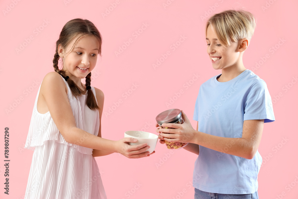 Cute little children with cereal rings on pink background Cute little children with cereal rings on pink background