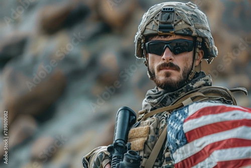 A soldier wearing a helmet and sunglasses holds an American flag.