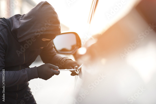 Close up car thief hand holding screwdriver tamper yank and glove black stealing automobile trying door handle to see if vehicle is unlocked trying to break into inside.. photo