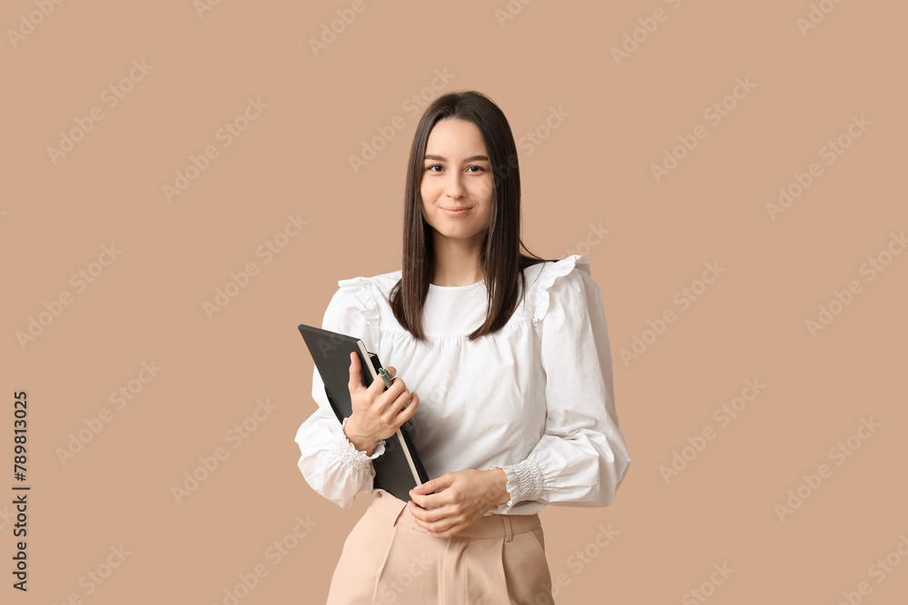 Young female writer with notebook on brown background Young female writer with notebook on brown background