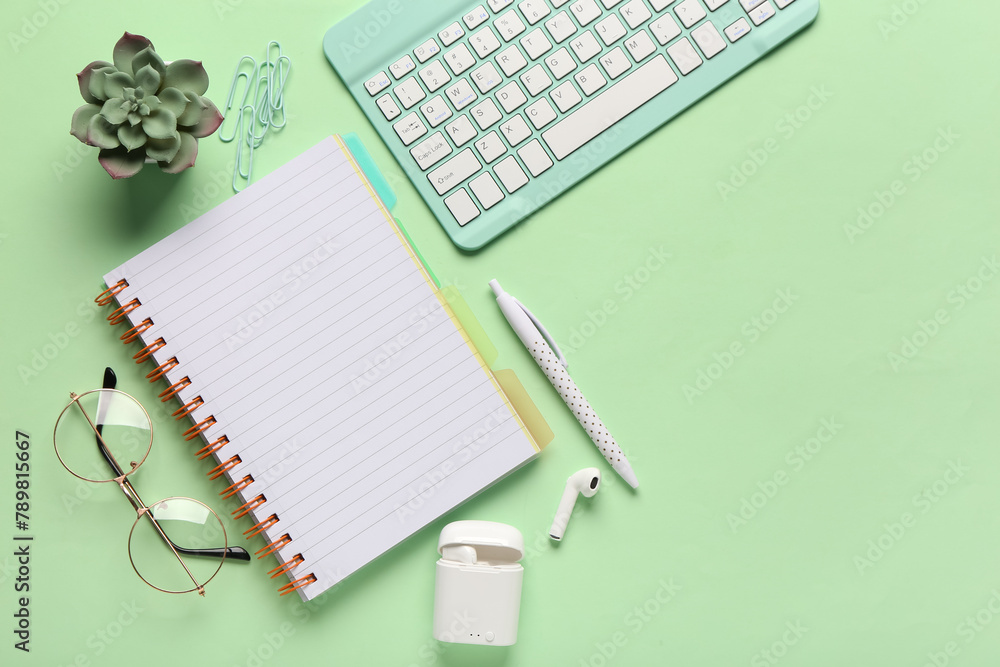 Composition with glasses, notebook and earphones on green background. Top view Composition with glasses, notebook and earphones on green background. Top view