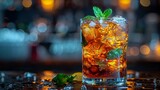   A glass topped with a mint sprig and surrounded by ice cubes holds an ice tea
