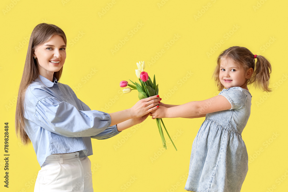 Little girl greeting her mom with Mothers Day with bouquet of tulips on yellow background Little girl greeting her mom with Mothers Day with bouquet of tulips on yellow background