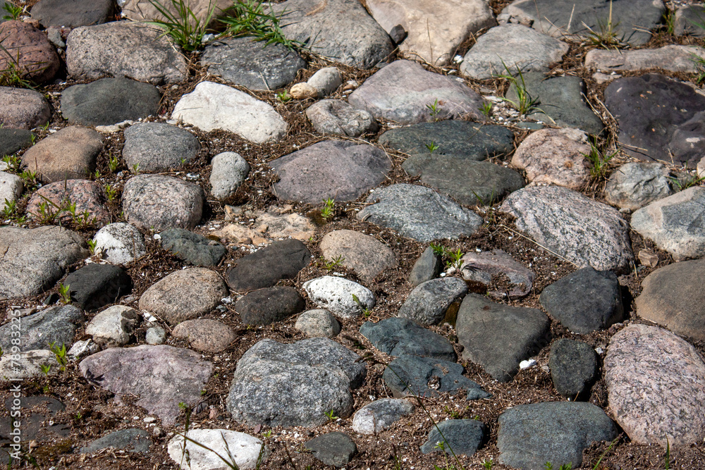 Fragment of a road made of granite stones. Paving stones on the sidewalk. Paving stones made of granite stones on an old road.