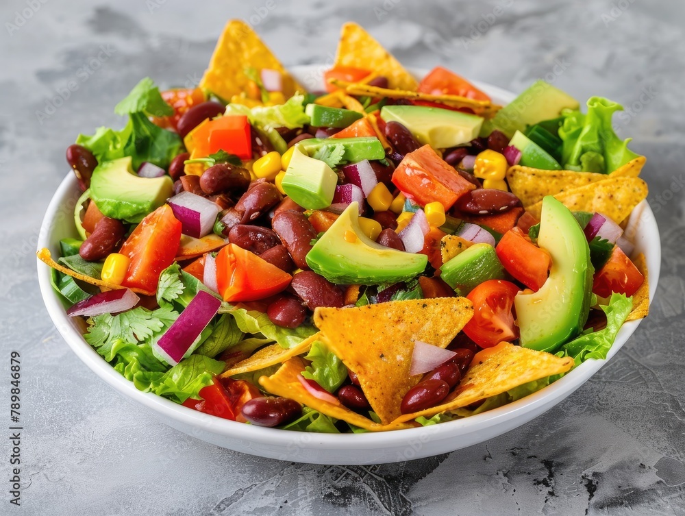 Bean salad with avocado and nachos in a white dish against a gray background! It's a Mexican food concept bursting with flavors and textures. Let's savor the combination of creamy avocado, 