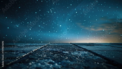 A dark blue night sky full of stars with a cobblestone street in the foreground. photo