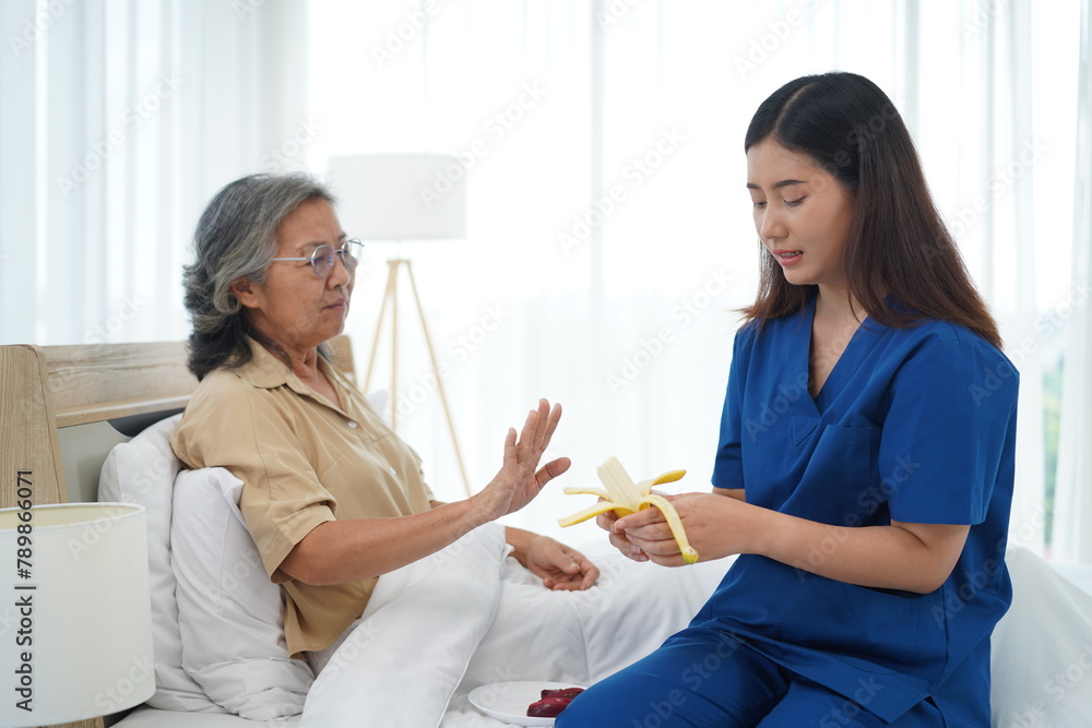 Asian senior woman raised her hand to refuse banana from caregiver Asian senior woman raised her hand to refuse banana from caregiver