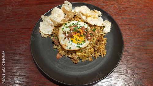 Gourmet Fried Rice with Sunny Side Up Egg and Crispy Toppings on Dark Plate