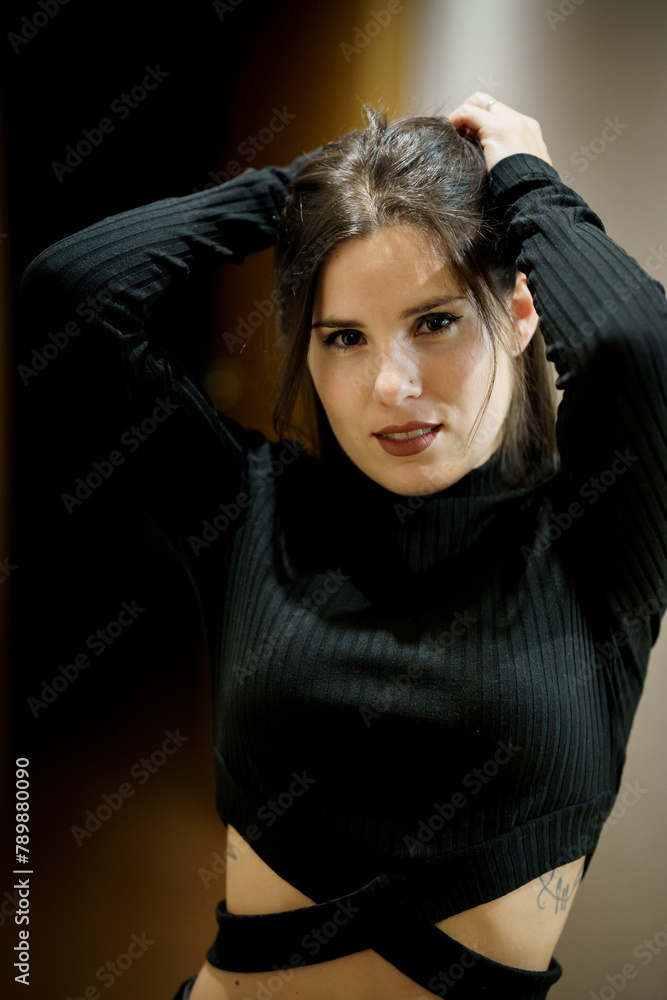Attractive young woman with make-up on, in close-up looking at the camera holding her hair Attractive young woman with make-up on, in close-up looking at the camera holding her hair