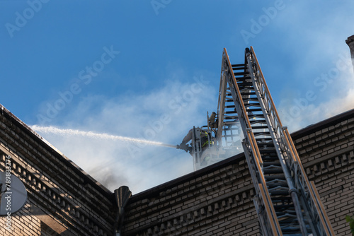 Rescuers are putting out the fire. A damaged residential building after a massive rocket attack. Heavy smoke. The house is on fire.