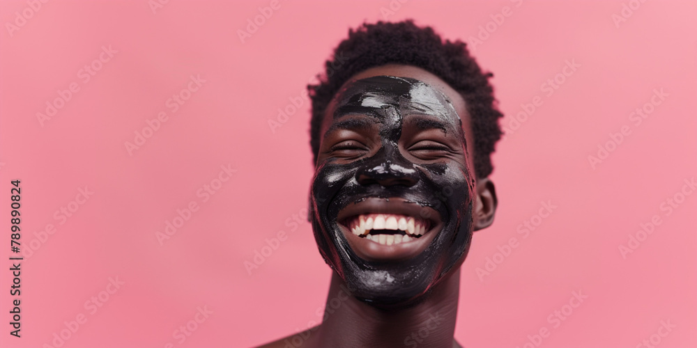African-American shocked man with clay facial mask and towel on head uses beauty products and cosmetic on blue studio background. Copy paste empty place for text. Skin care and peeling concept