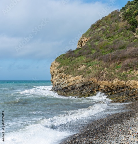 not calm Black Sea, beach and steep coast near the green wooded mountains of the Western Caucasus not far from the village of Abrau (South of Russia) on a sunny spring day