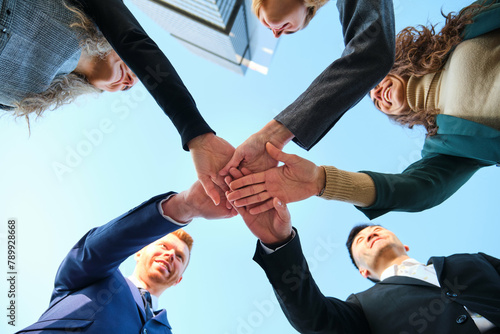Low angle view of businesspeople stack hands, team building, support, planning, mission and trust. Corporate community success, solidarity, and collaboration with synergy.