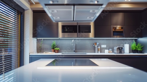 A kitchen with a white countertop and black cabinets. The countertop is clean and shiny, and the cabinets are sleek and modern. There is a sink, a microwave, and an oven in the kitchen © Bouchra