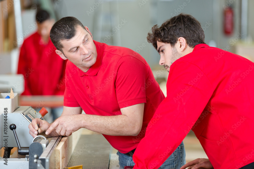 man showing trainee how to set up machine in workshop man showing trainee how to set up machine in workshop