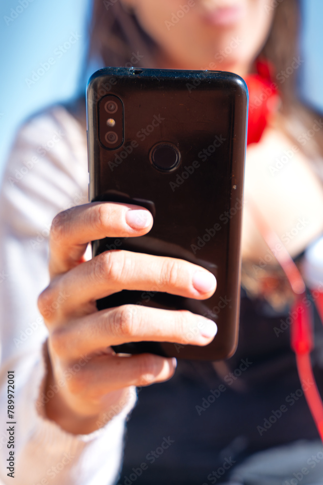 Vertical portrait Unrecognizable young woman using smartphone app outdoors.