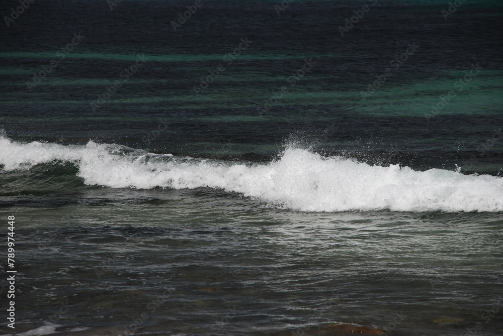 Fototapeta premium waves at the sea shore, rollingon blue ocean water, white cap