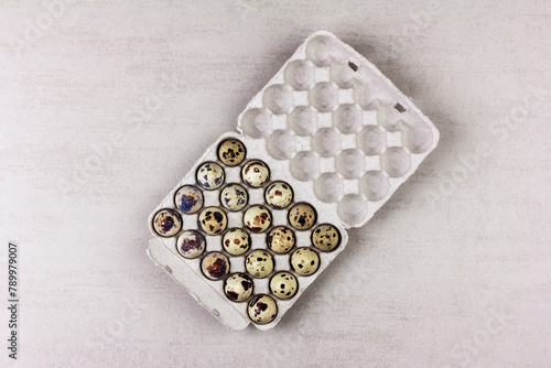 an open paper tray with quail eggs on a gray background with a copy space, top view