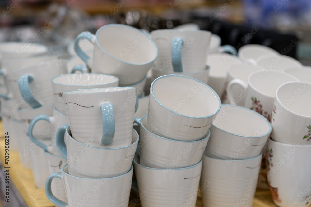 A stack of white mugs and plates in the store for sale. White and clean dishes. A stack of white mugs and plates in the store for sale. White and clean dishes.