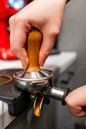 Close-up of a person tamping freshly ground coffee into a portafilter, preparing to brew a perfect espresso. A moment in the art of coffee making photo