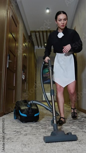 Hotel maid vacuuming in hallway. Vertical video